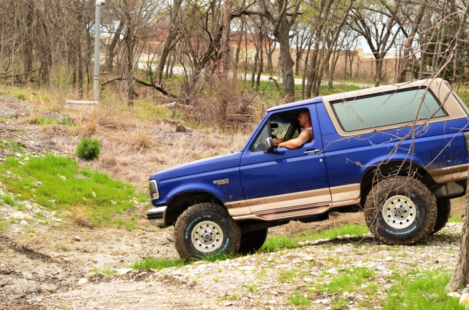 Blue 1996 Ford Bronco driving on a dirt trail