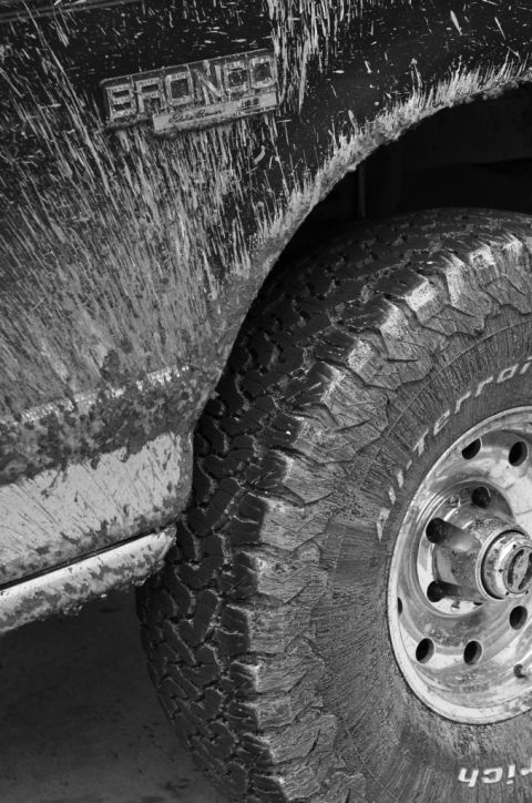 1996 Ford Bronco - Close-up of a mud-covered 1996 Ford Bronco's fender and wheel, showing the 'BRONCO' badging.