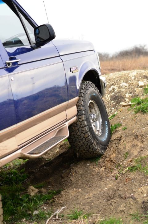 1996 Ford Bronco - Blue 1996 Ford Bronco driving off-road on a dirt hill.