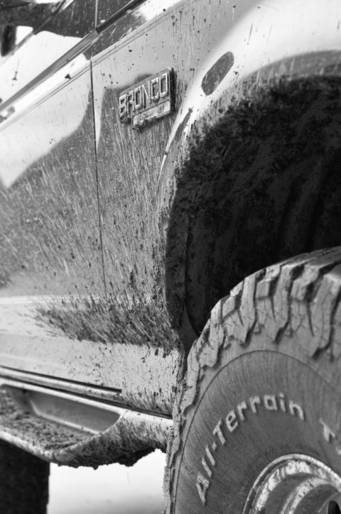 1996 Ford Bronco - Muddy 1996 Ford Bronco side view, showing the BRONCO emblem and tire tread.