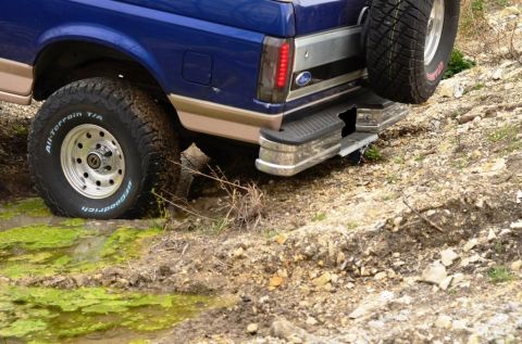 1996 Ford Bronco - This Ford Bronco is navigating a muddy trail with its rear end visible.