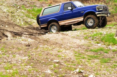 1996 Ford Bronco - 1996 Ford Bronco navigating a muddy off-road trail.