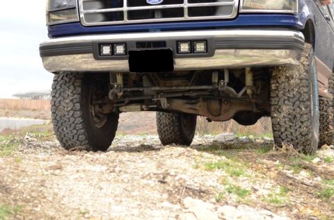 1996 Ford Bronco - Front view of a blue Ford truck with off-road tires and aftermarket lights.