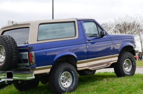 1996 Ford Bronco - This 1996 Ford Bronco is shown from a three-quarter front angle, highlighting its blue paint and tan removable top.