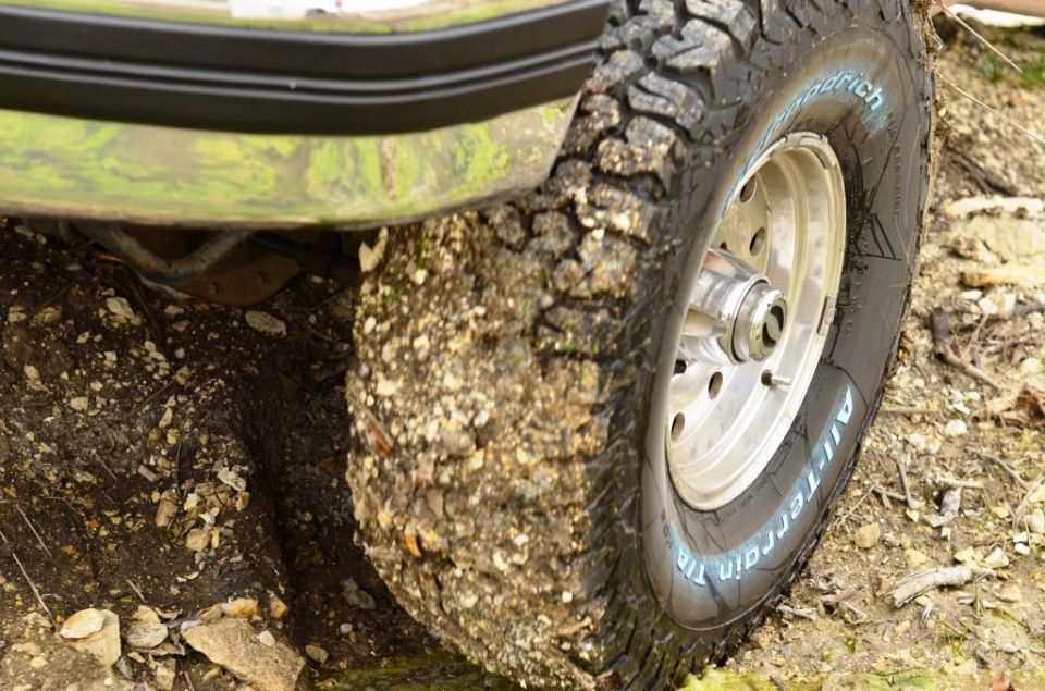Green fender above muddy off-road tire with 'All-Terrain T/A' text