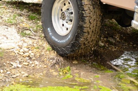 1996 Ford Bronco - Off-road tire navigating a muddy, watery trail. Supermotors.net logo is present.