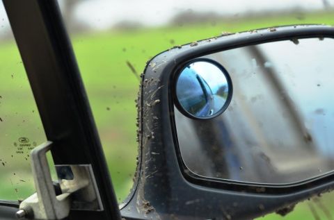 1996 Ford Bronco - Mud splatters cover the side mirror and window of an off-road vehicle.