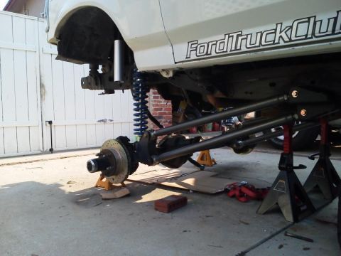1981 Ford Bronco - The vehicle's front end is elevated on jack stands, revealing its suspension system during a modification process.
