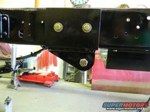1981 Ford Bronco - Close-up view of vehicle frame and suspension components, with a red hydraulic jack and jack stands in the background.