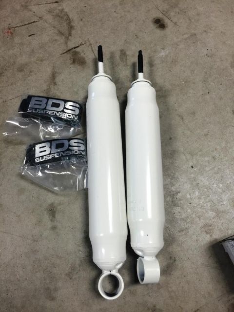 1996 Ford Bronco - Two white BDS Suspension shock absorbers are laid out on a concrete surface next to their packaging.