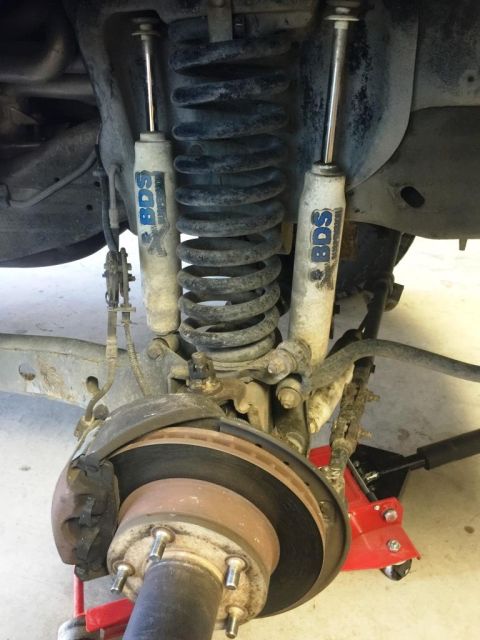 1996 Ford Bronco - Close-up view of the front suspension components, including shocks, springs, and brake assembly.