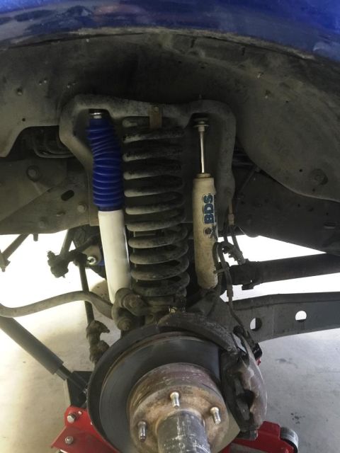 1996 Ford Bronco - Close-up view of vehicle suspension components, including shock absorbers and a coil spring.