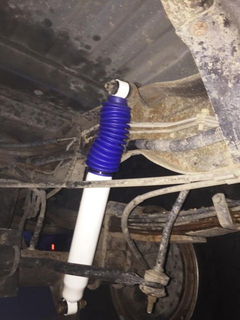 1996 Ford Bronco - A new white and blue shock absorber is installed on the rear suspension of a vehicle.