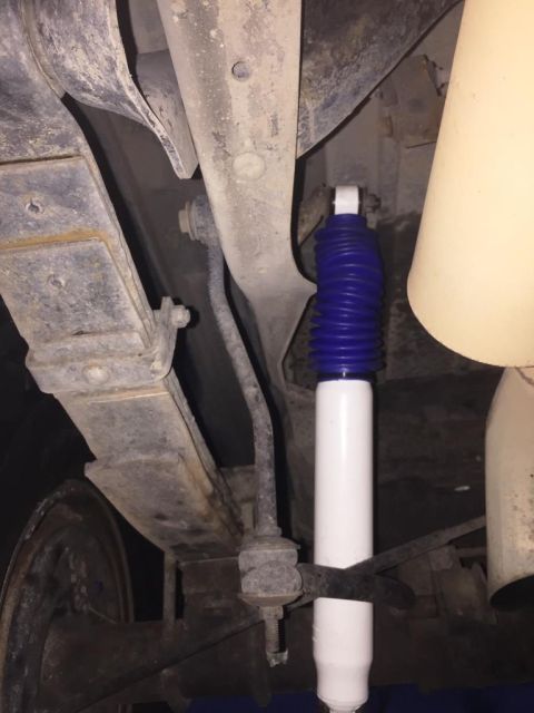 1996 Ford Bronco - Underneath view of a vehicle's rear suspension, showing a leaf spring and a shock absorber.