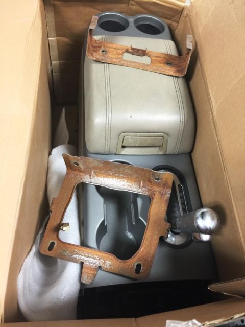1996 Ford Bronco - Several car interior parts, including a center console and gear shifter, are packed in a cardboard box.