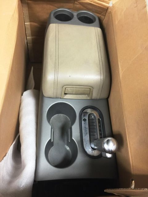 1996 Ford Bronco - Center console assembly with cup holders and gear shifter, partially wrapped in protective material within a box.