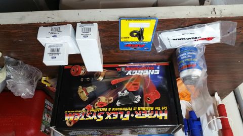 1995 Ford Mustang - A collection of automotive parts are laid out on a wooden surface. Visible items include several boxes labeled "Ford", an ARP fastener asse…