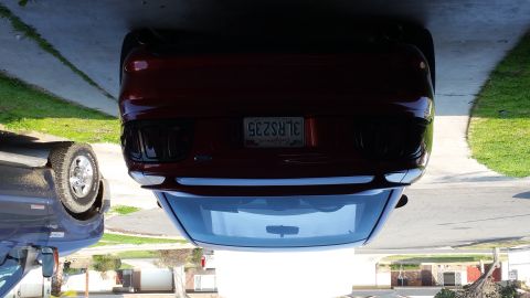 1995 Ford Mustang - The rear view of a dark red Ford Mustang is shown parked in a driveway. The license plate reads "3LRS235" and is from California.