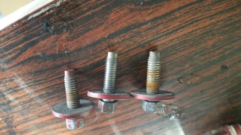 1995 Ford Mustang - Three bolts with washers and nuts are laid out on a wooden surface. The bolts appear to be used and have some rust and wear.