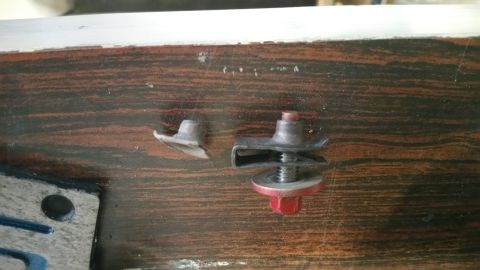 1995 Ford Mustang - Two metal fasteners are displayed on a wooden surface. One fastener is a single piece with a flared base and a small post. The other fasten…