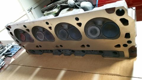 1995 Ford Mustang - A close-up, angled view of a disassembled aluminum V8 engine cylinder head, showing the intake and exhaust valves within their respective p…
