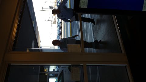 1995 Ford Mustang - A man in a light blue shirt and dark pants is reflected in a glass door. He is holding a piece of paper in his left hand and appears to be…