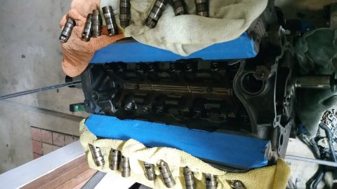 1995 Ford Mustang - A disassembled engine block is shown with several valve lifters resting on a towel. Blue painter's tape is used to mask off sections of the…