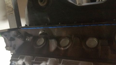 1995 Ford Mustang - A close-up view of a dark-colored engine block with a blue gasket visible along the top edge. Several circular openings, likely cylinder bo…