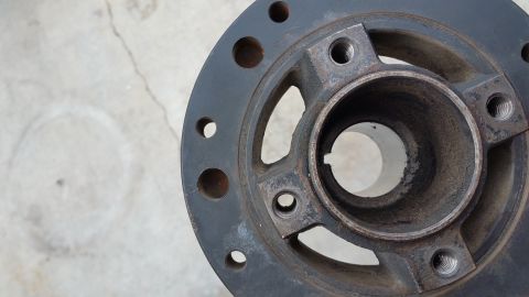 1995 Ford Mustang - A close-up, overhead view of a dark gray metal automotive part, likely a pulley or hub, with multiple bolt holes and a central cylindrical…
