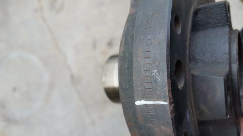 1995 Ford Mustang - A close-up view of a black metal disc with stamped markings and tick marks, possibly a brake rotor or pulley, with a silver metal hub visib…