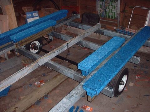 1996 Ford Taurus - A trailer frame with blue carpeted bunks is shown, with one wheel visible and parts scattered on the floor.