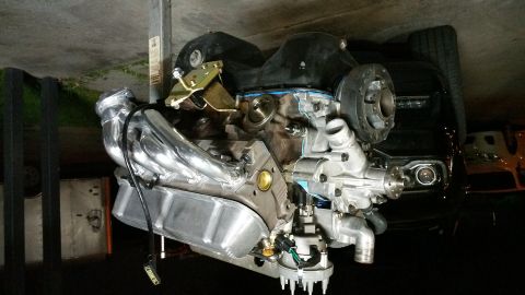 1995 Ford Mustang - A V8 engine with chrome exhaust headers and a polished aluminum water pump is mounted on an engine hoist. The engine appears to be a Ford V…
