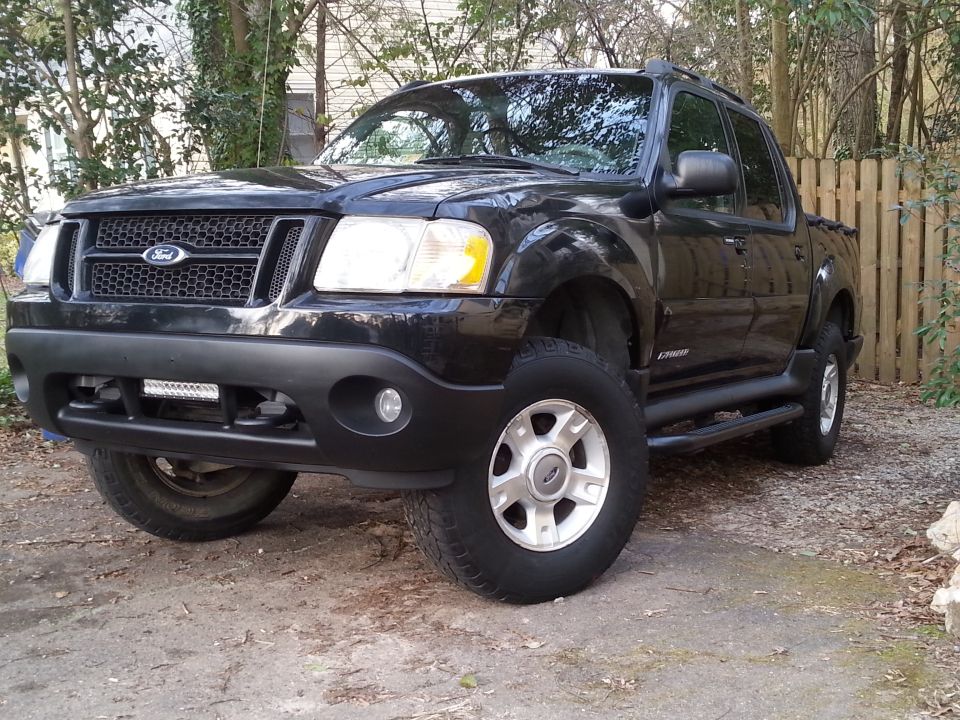 Black Ford Explorer Sport Trac with custom grille, wheels, and light bar.