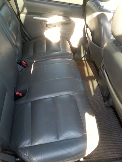 2001 Ford Explorer - The interior of a Ford Explorer shows the rear leather seats and floor mats. Sunlight streams in from the side window, illuminating the sea…