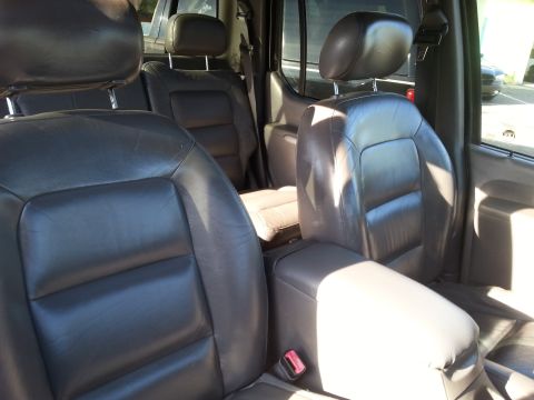 2001 Ford Explorer - The interior of a 2001 Ford Explorer shows the front leather seats, center console, and part of the rear seats. The seats are dark brown an…