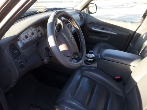 2001 Ford Explorer - The interior of a Ford Explorer is shown, focusing on the driver's side dashboard, steering wheel, and front seats. A bottle of Powerade is…
