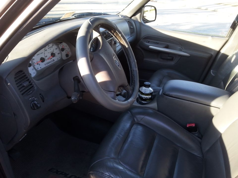 Interior of a Ford Explorer showing dashboard, steering wheel, seats, and a Powerade bottle.