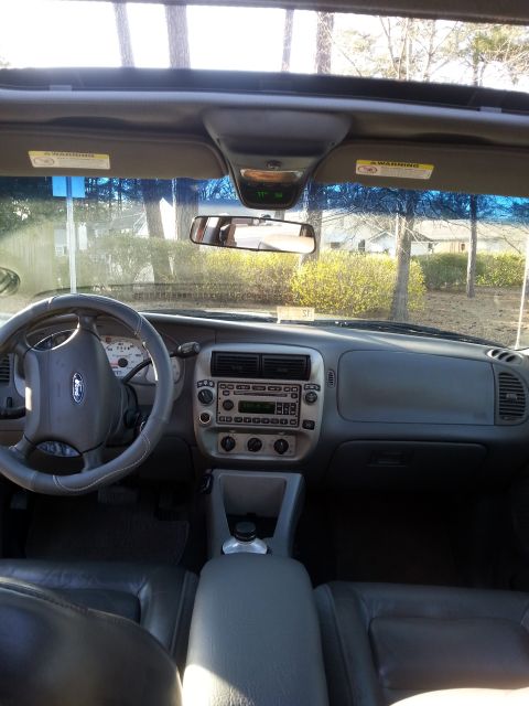 2001 Ford Explorer - The interior of a 2001 Ford Explorer Sport Trac is shown, featuring a gray dashboard, steering wheel with a Ford logo, and leather seats. T…
