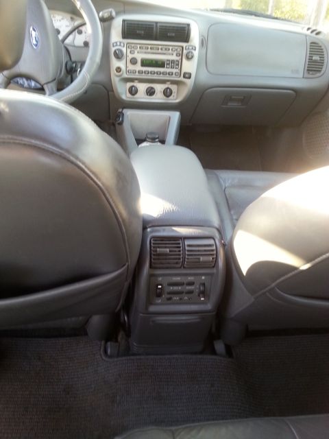2001 Ford Explorer - The interior of a Ford Explorer from the rear seats, showing the center console with climate controls and rear air vents, as well as the da…