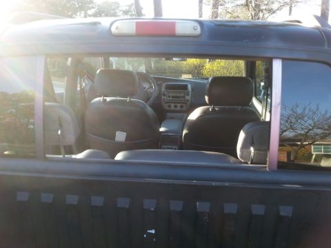 2001 Ford Explorer - View through the rear window of a dark-colored Ford Explorer Sport Trac, showing the interior with dark leather seats and dashboard.