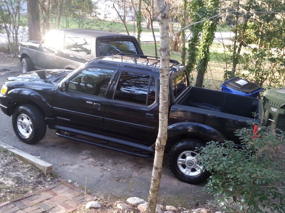 Black Ford Explorer Sport Trac parked next to a Bronco-style SUV.