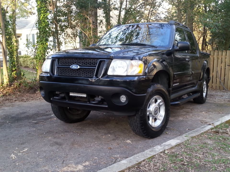 Black Ford Sport Trac pickup truck with aftermarket LED light bar on front bumper.