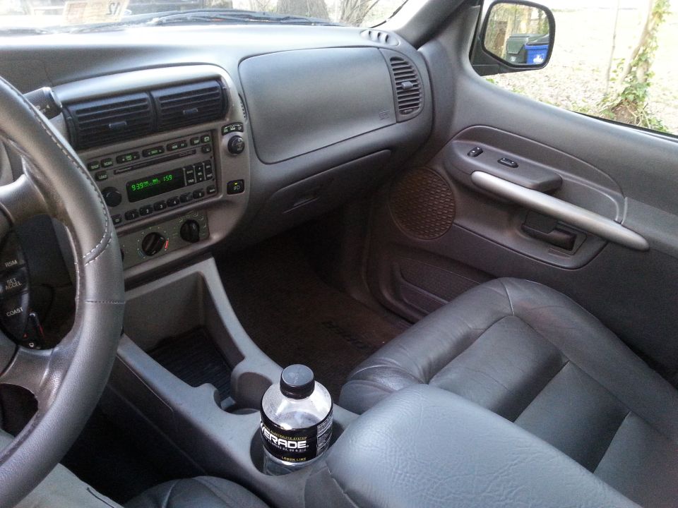 Interior of a Ford Explorer showing dashboard, steering wheel, door panel, and cup holder with Gatorade.