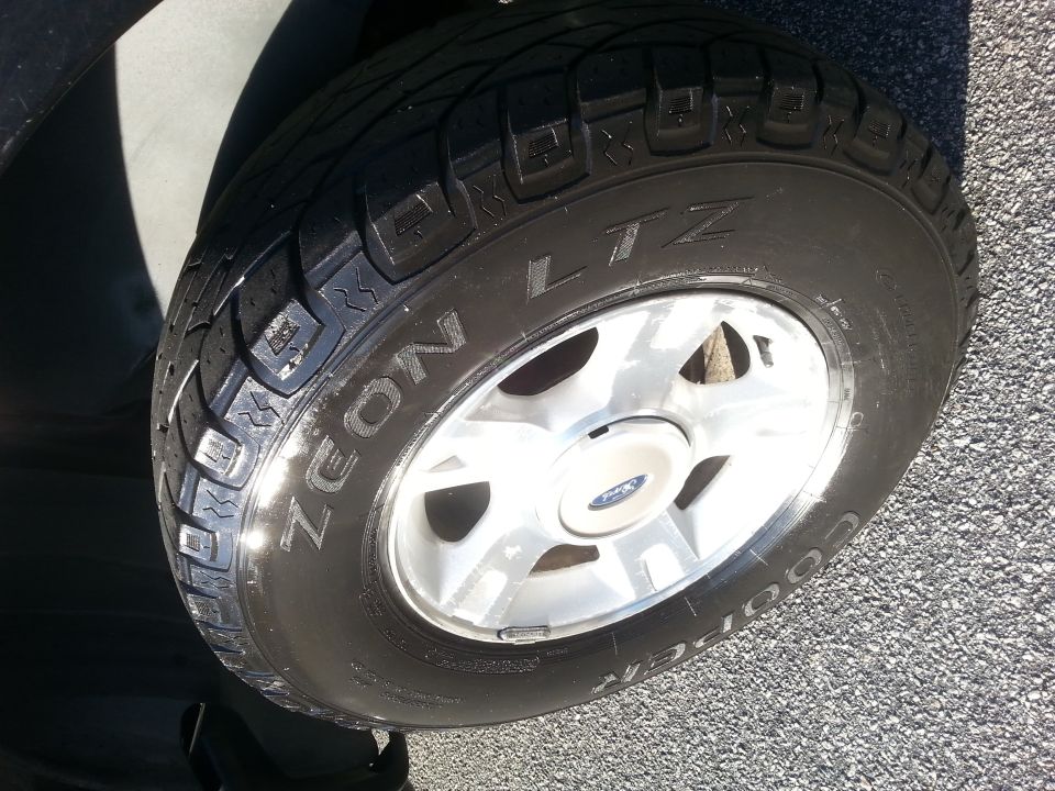Close-up of a Cooper Zeon LTZ tire on a silver alloy wheel of a Ford Explorer.