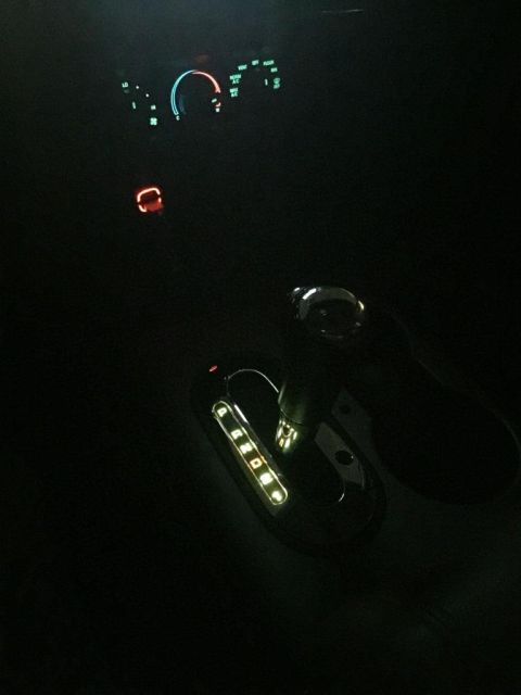 1996 Ford Bronco - Illuminated gear selector and dashboard lights visible in the dark interior of a vehicle.