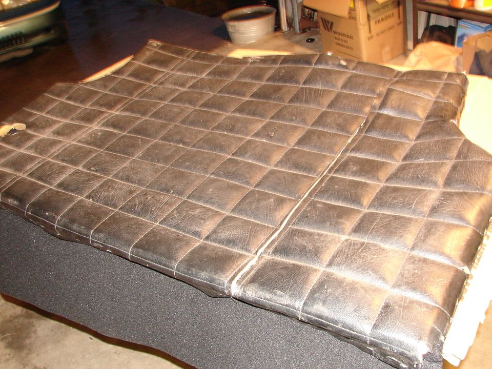 Black quilted seat covers with diamond stitching, showing wear