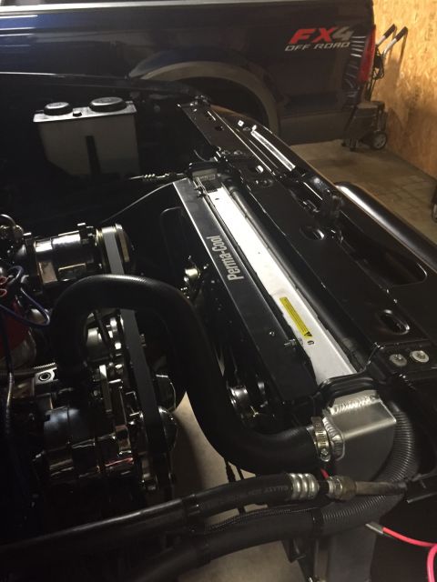 1982 Ford Bronco - The engine bay of a vehicle shows a polished aluminum radiator with "Perma-Cool" branding, a black fan shroud, and various hoses and belts.…