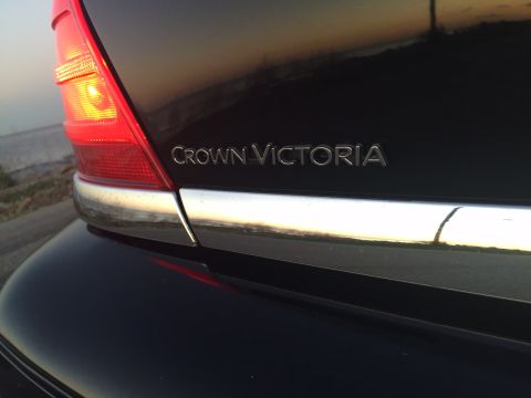 2008 Ford Crown Victoria - Close-up of the rear of a black Ford Crown Victoria, showing the taillight and the "CROWN VICTORIA" badging above a chrome accent strip.