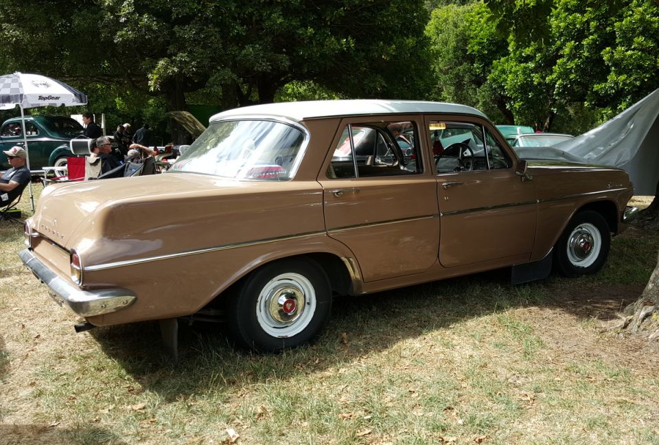 Brown 1960s sedan with white roof, rear passenger side view.