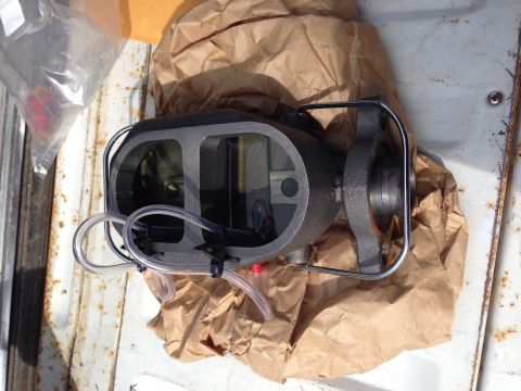 1979 Ford Bronco - A new brake master cylinder is shown, partially wrapped in brown paper, on a weathered surface.